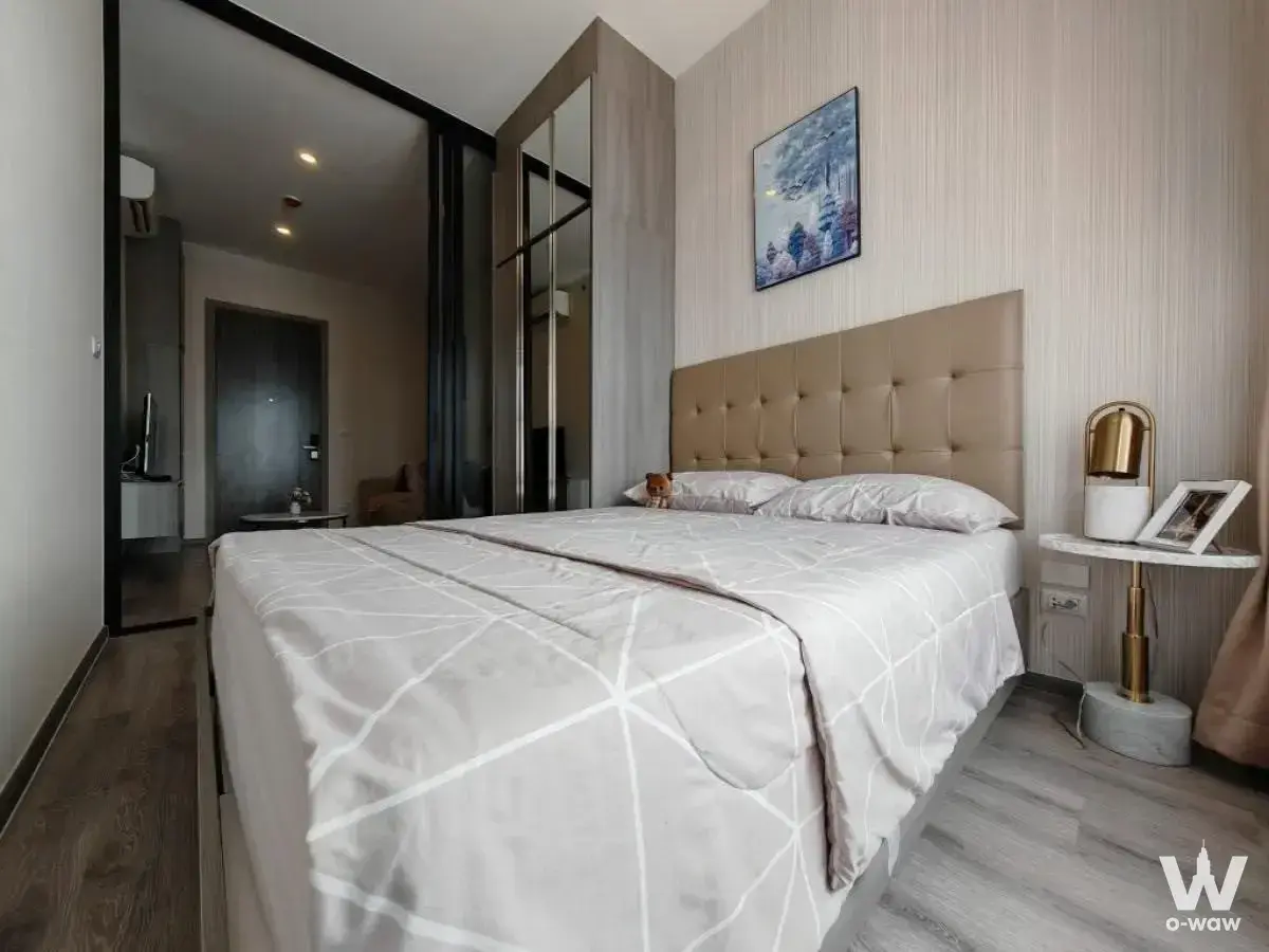 Master bedroom in a 1-bed condo for sale at KnightsBridge Prime Onnut, with tan leather headboard and glass partition