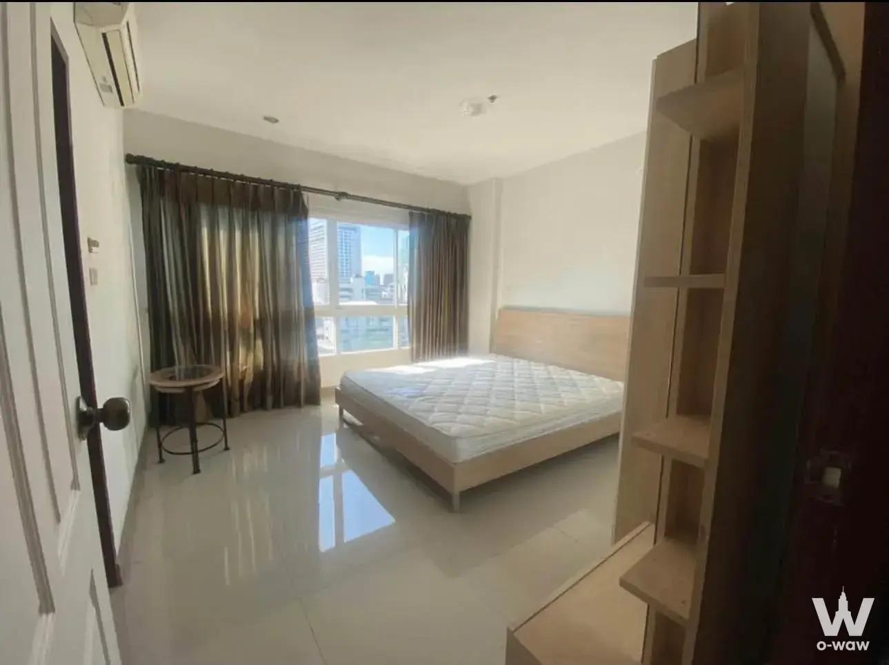 Modern 1-bed condo bedroom for rent in PG Rama 9 featuring city skyline view, glass side table, and minimalist style