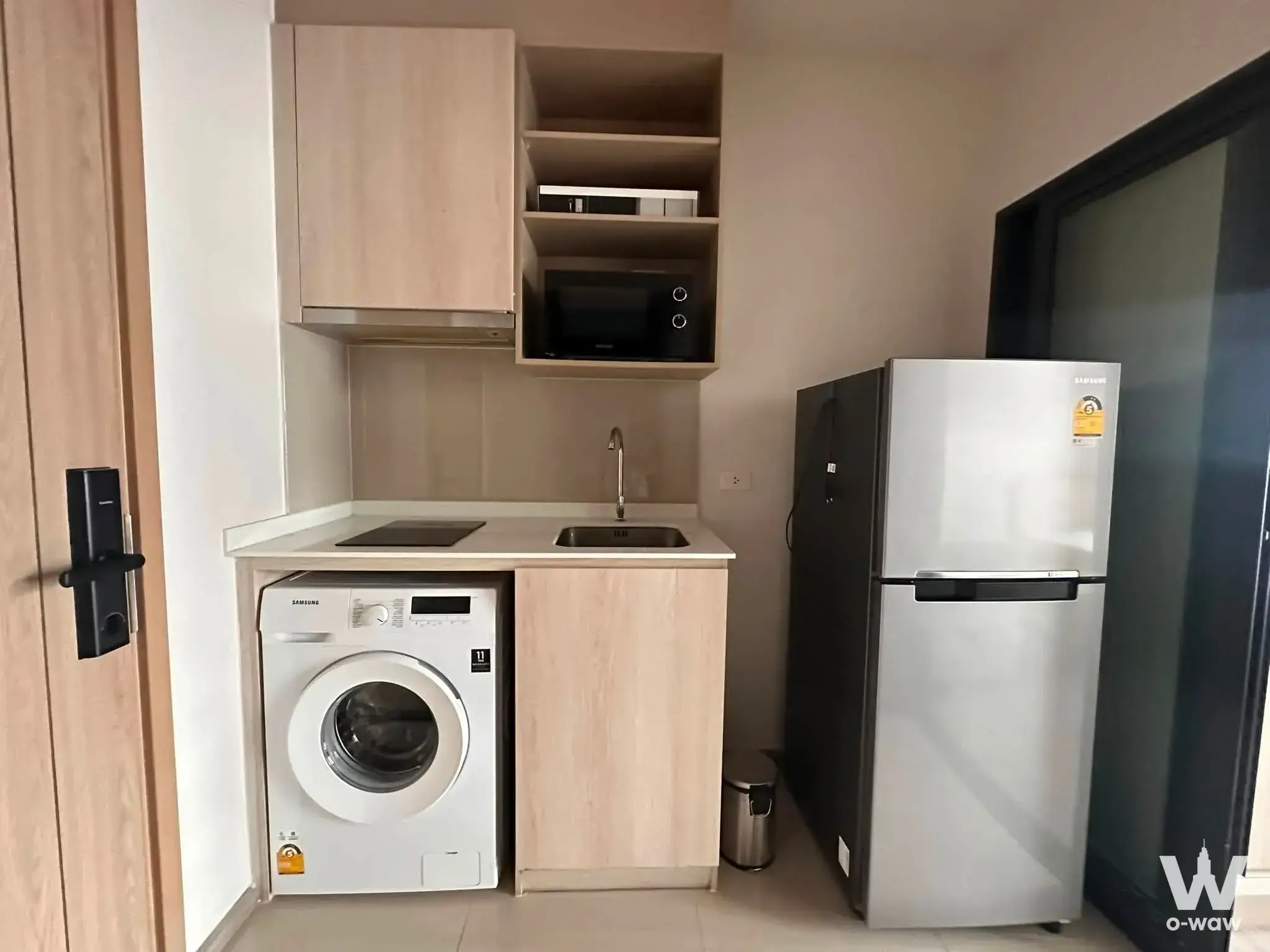 Compact kitchenette in a NIA by Sansiri rental with induction cooktop and washing machine