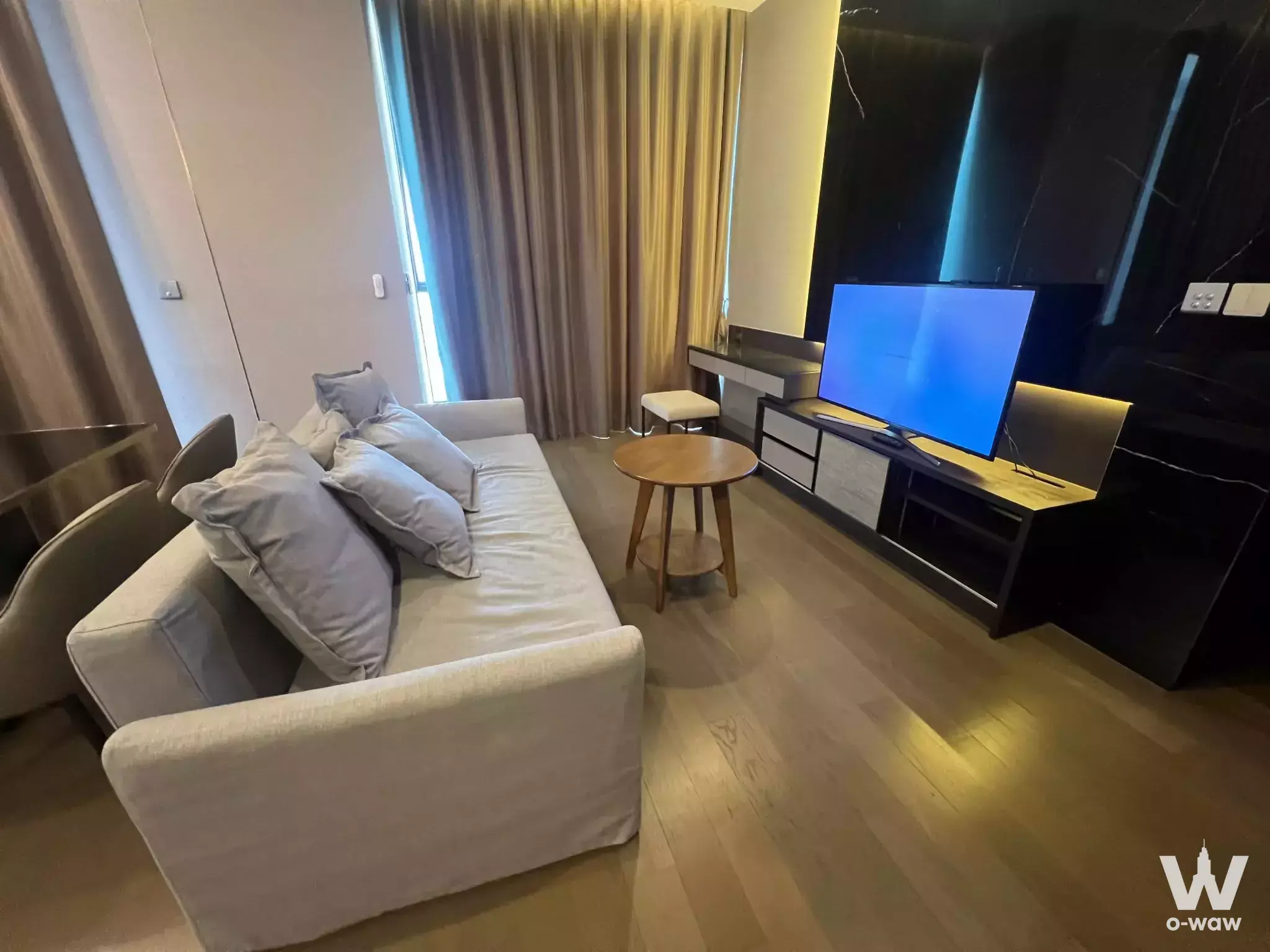 Modern living room in a THE ESSE SINGHA COMPLEX condo with black marble accent wall and warm cove lighting