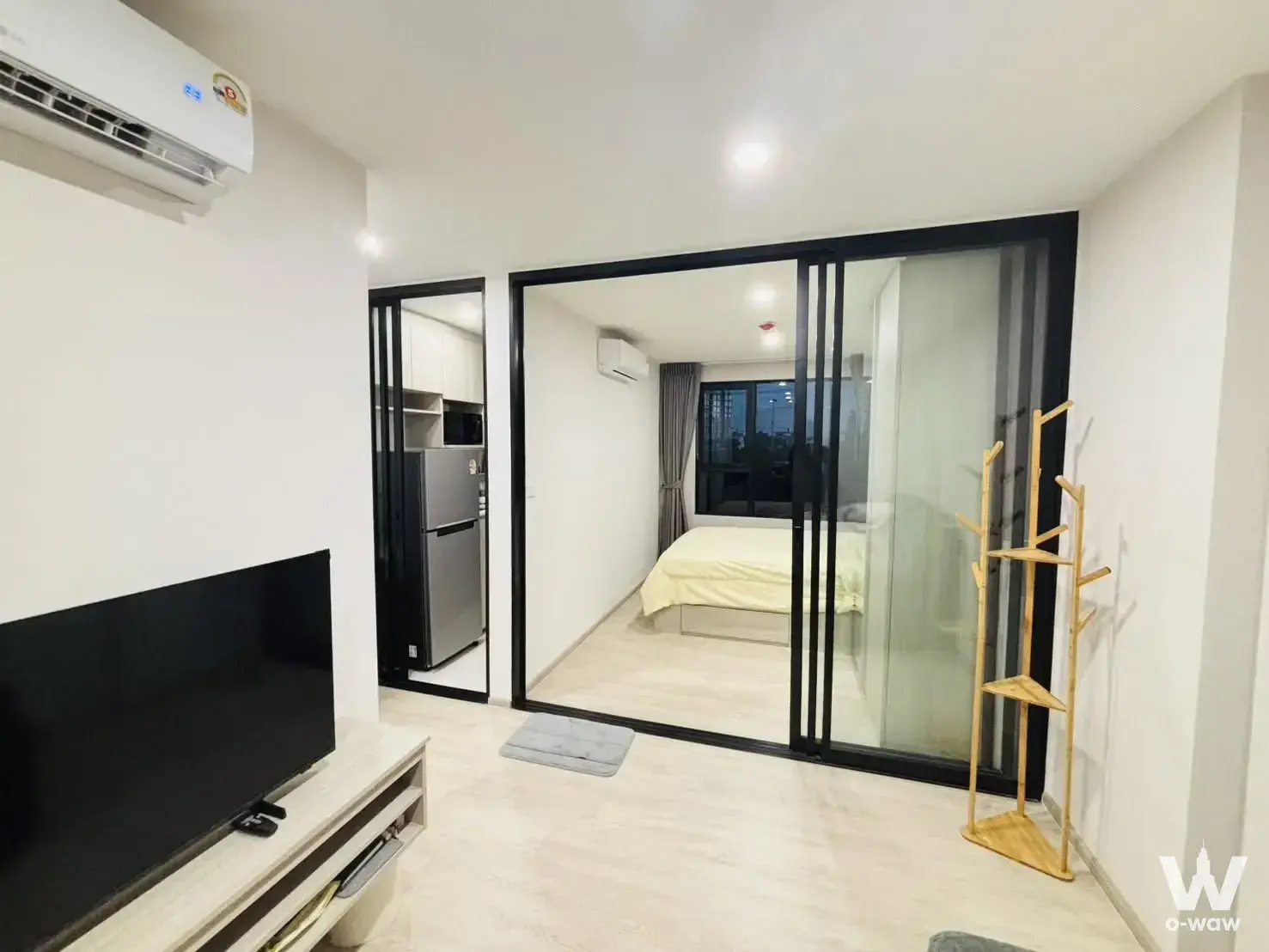 Open plan studio layout with sliding glass bedroom doors and a compact kitchenette in an Origin Plug & Play condo