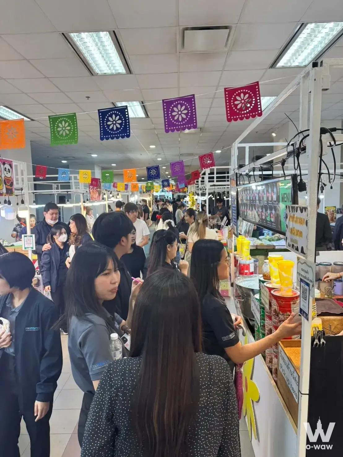 Crowded indoor market hall with colorful paper banners and food stalls in the NT TOWER condo complex