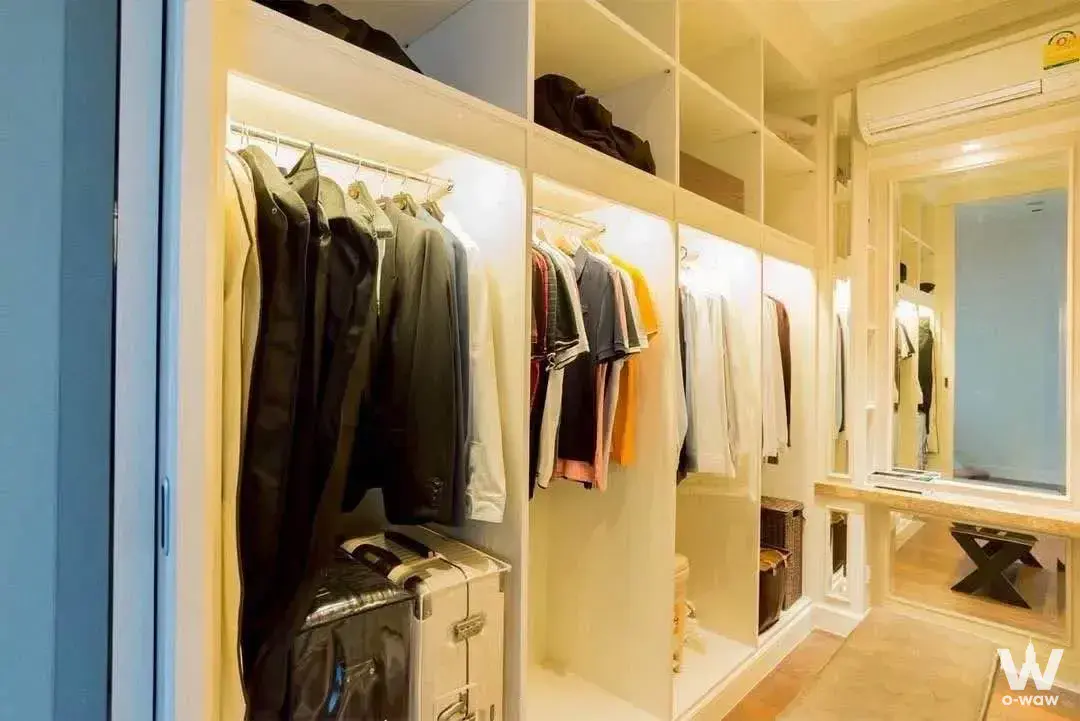Walk-in closet with white shelving and LED lighting in Narasiri Bangna house