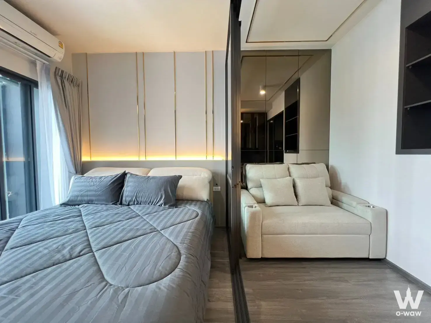 Luxury bedroom in IdeO Sukhumvit Rama 4 with gold-trimmed wall and glass partition to lounge