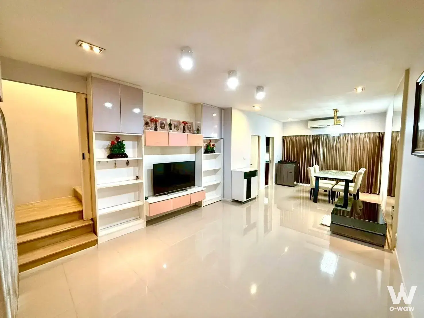 Living area in Baan Klang Muang townhouse with glossy cream floors and pink-accented wall unit