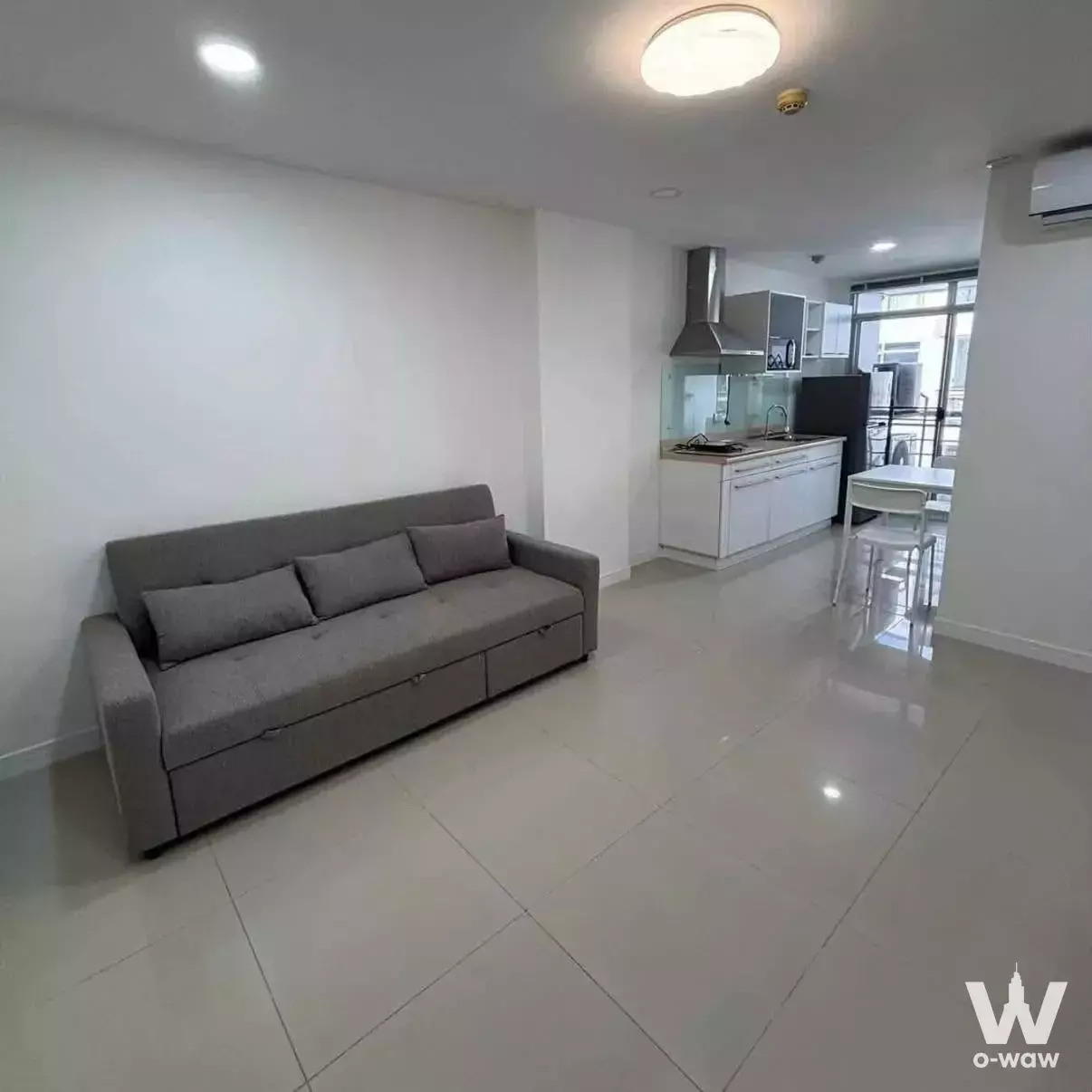 Grey sofa and compact kitchen in a 1-bed condo for rent at The Link Sukhumvit 50