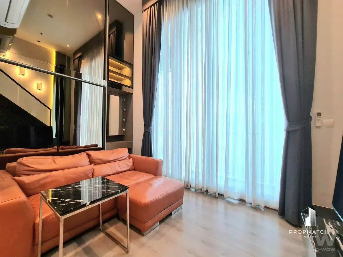 1-bed condo for rent in The Reserve Phahol-Pradipat living room with terracotta orange sectional sofa and floor-to-ceiling