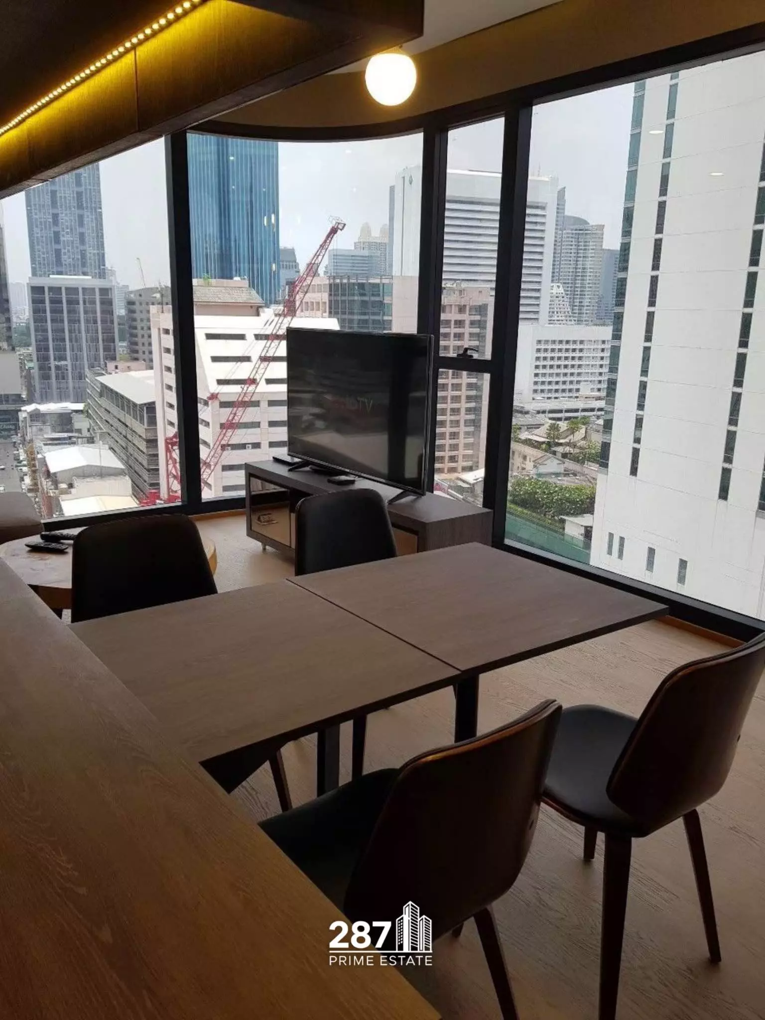 Dining area in Ashton Chula-Silom with dark wood tables and floor-to-ceiling corner windows