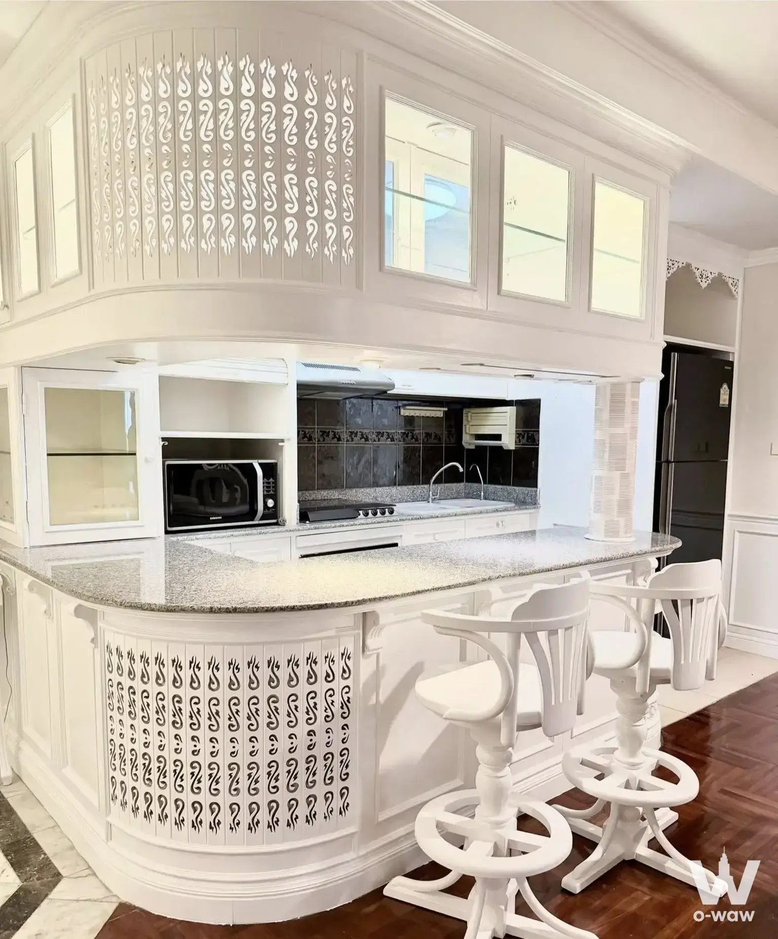 Luxurious classical kitchen in a 2-bed Las Colinas condo featuring ornate white cabinetry and a curved island
