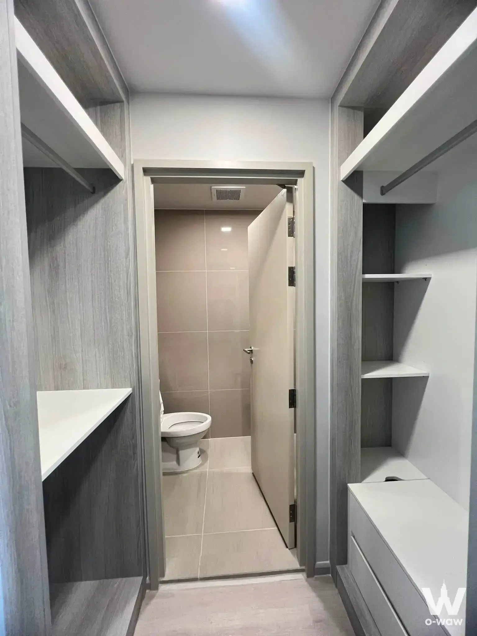 Walk-in closet with grey wood-grain cabinetry and open shelving in this 1-bed condo for rent at COBE Ratchada-Rama 9