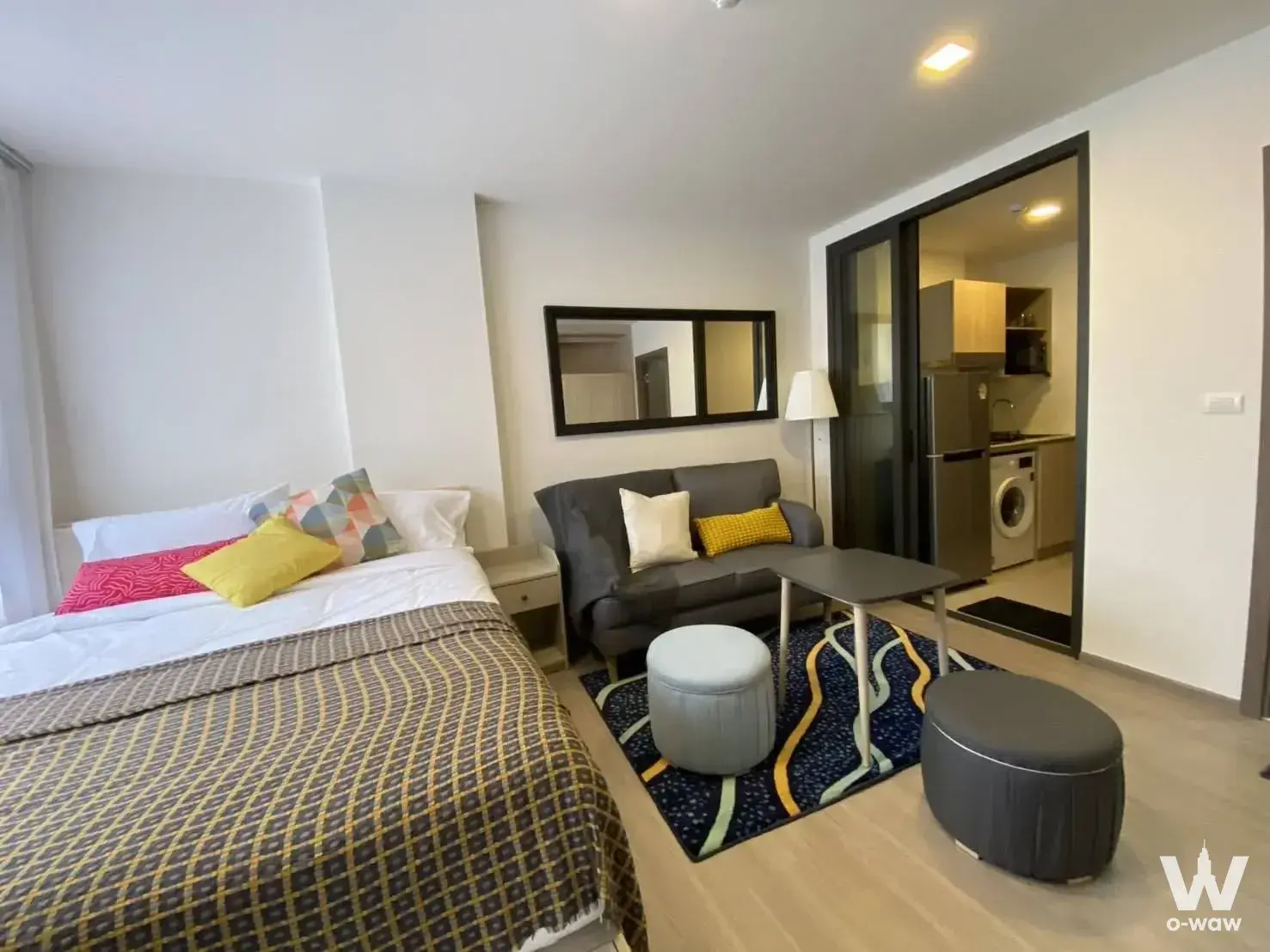 Furnished studio in a 1-bed condo at The Muve Pradipat showing a sofa, rug, and kitchenette access