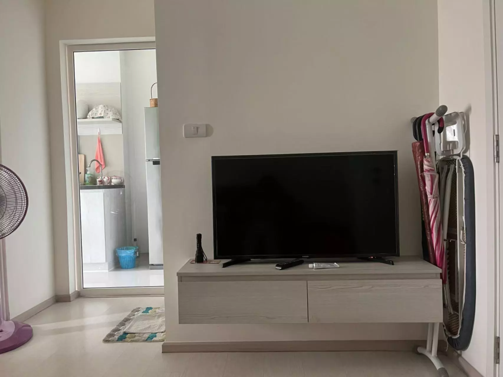 Living room in Aspire Erawan Prime condo with beige wood flooring and floating TV console