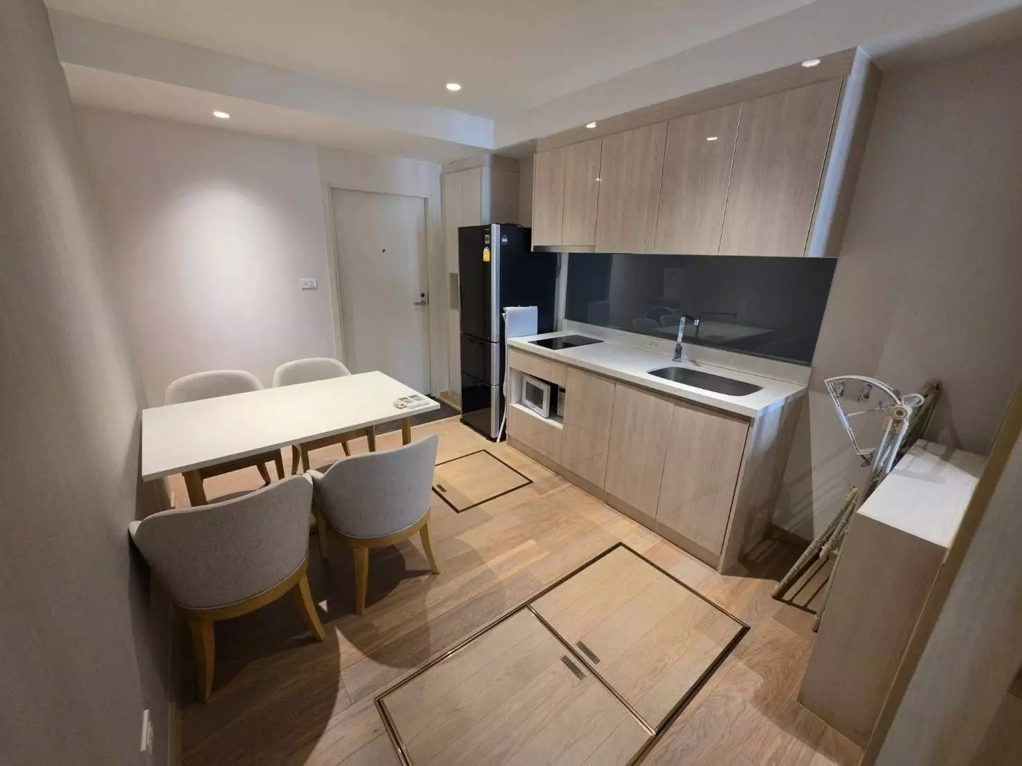 Dining area in Runesu Thonglor 5 with grey chairs and a compact galley kitchen