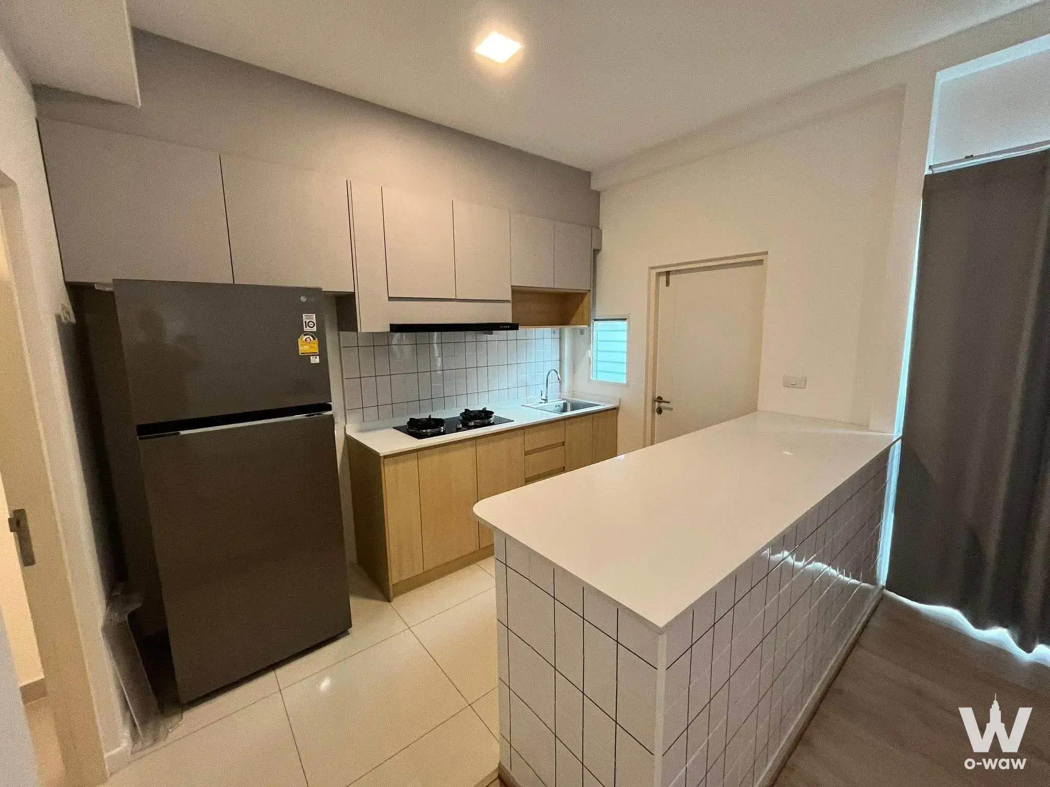 Modern kitchen in the Indy 2 Bangna-Ramkhamhaeng townhouse with white quartz counters and light wood cabinets