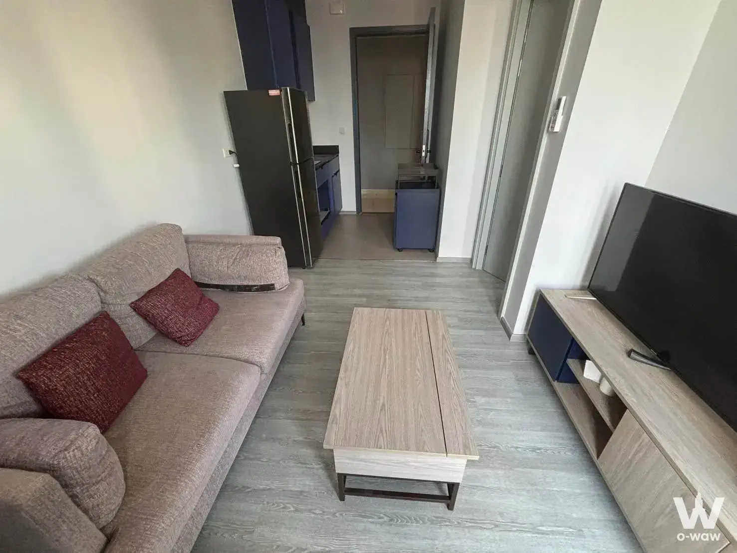 Living area in an XT Ekkamai rental with grey sofa, wood coffee table, and open-plan kitchen access