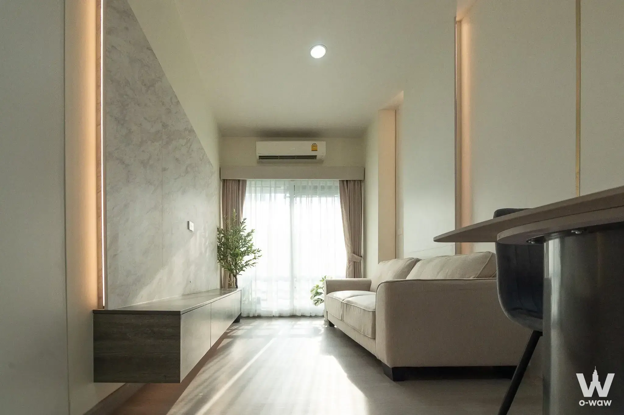 Minimalist living room in The Fourwings Residence featuring grey marble feature wall and floating media console