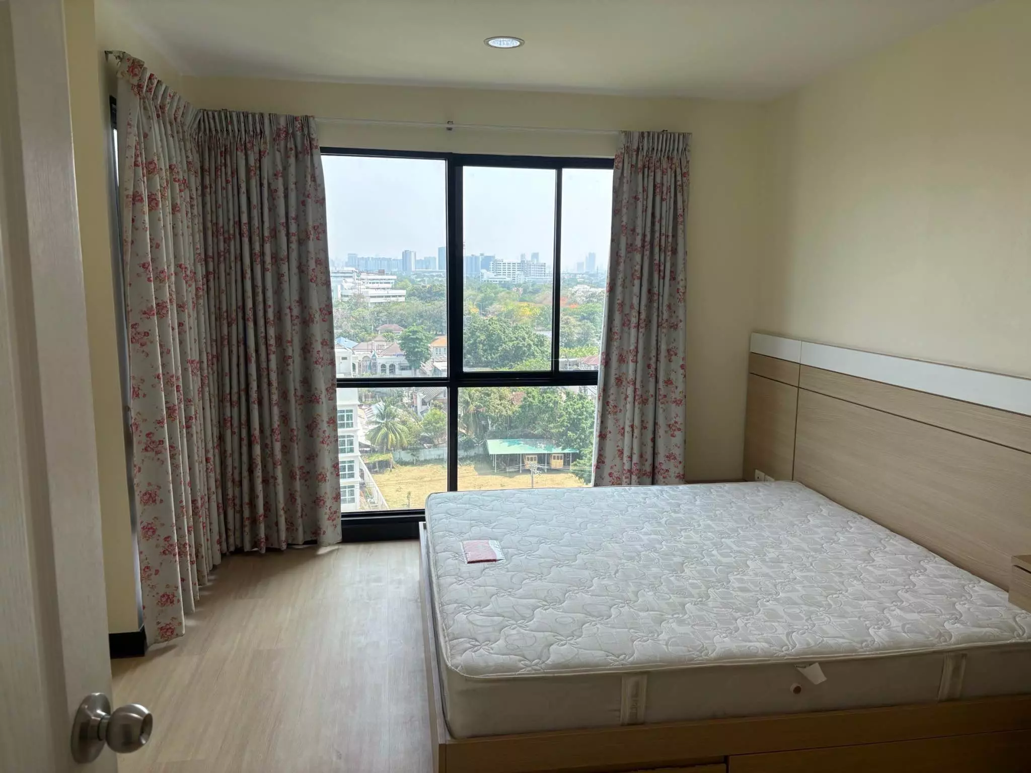 Queen bed in a 1-bed condo for rent at Akesin Place with floor-to-ceiling windows and city skyline views