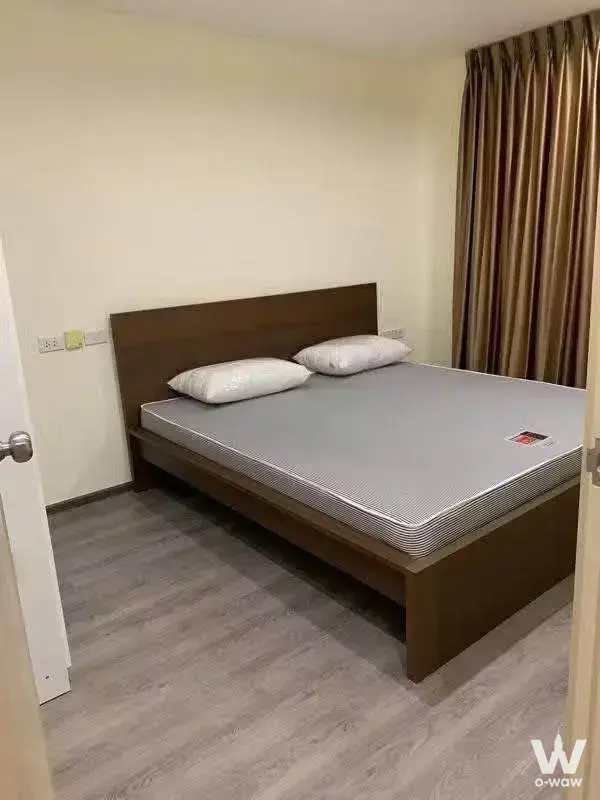 Empty modern condo bedroom in Rich Park Triple Station with dark wood bed frame and striped curtains