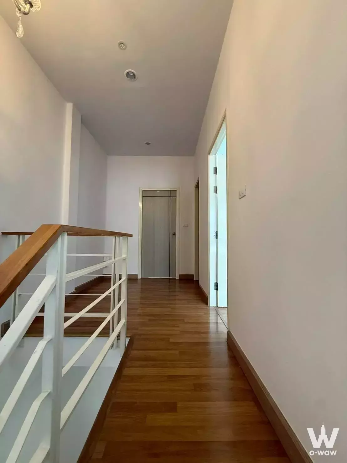 Duplex hallway in Baan Klang Muang Rama 9 with wood floors, stairwell void, and elevator entrance