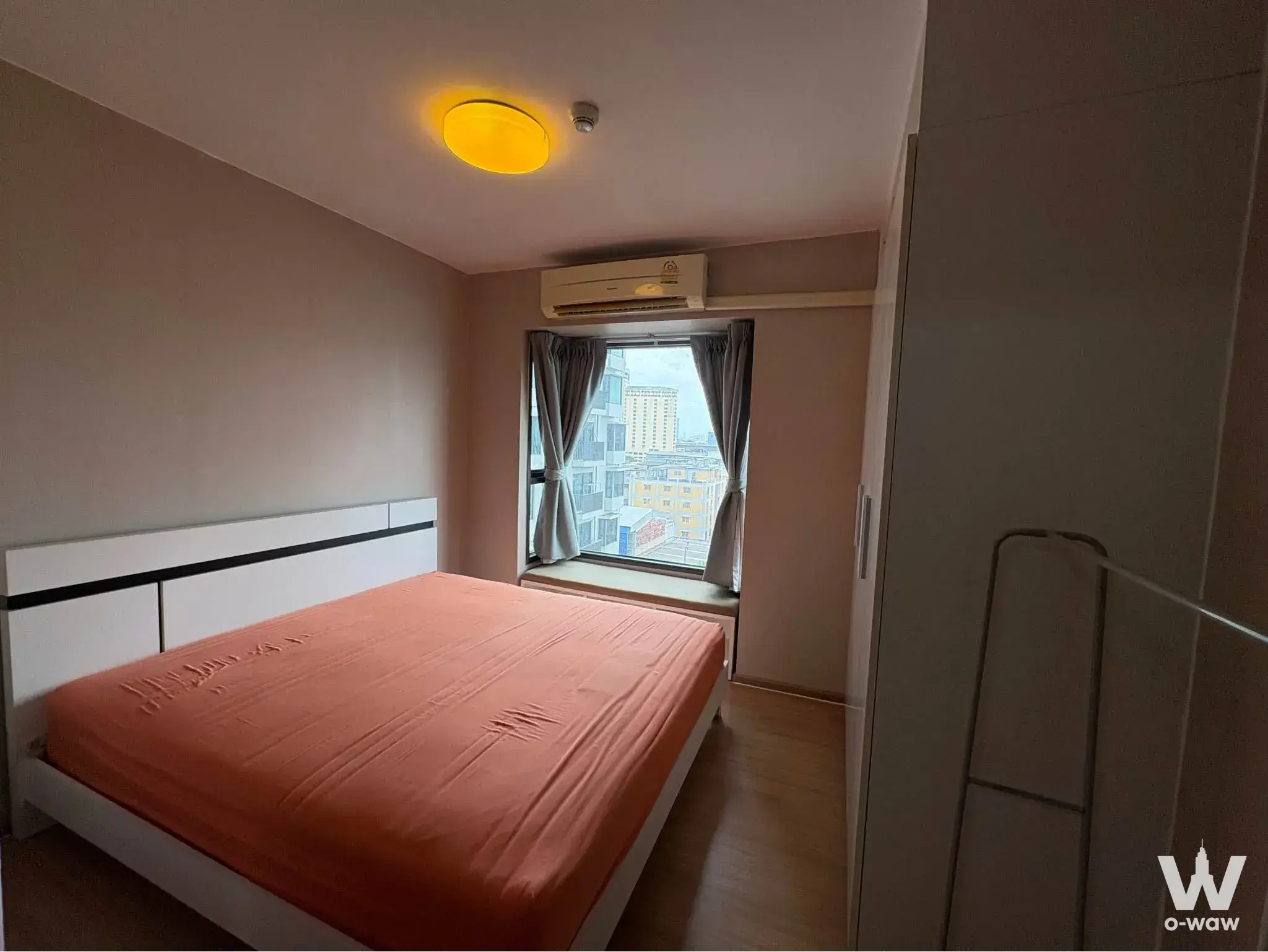 1-bed condo for rent in Fuse Mobius showing a bedroom with an orange accent bed, window seat, and city view