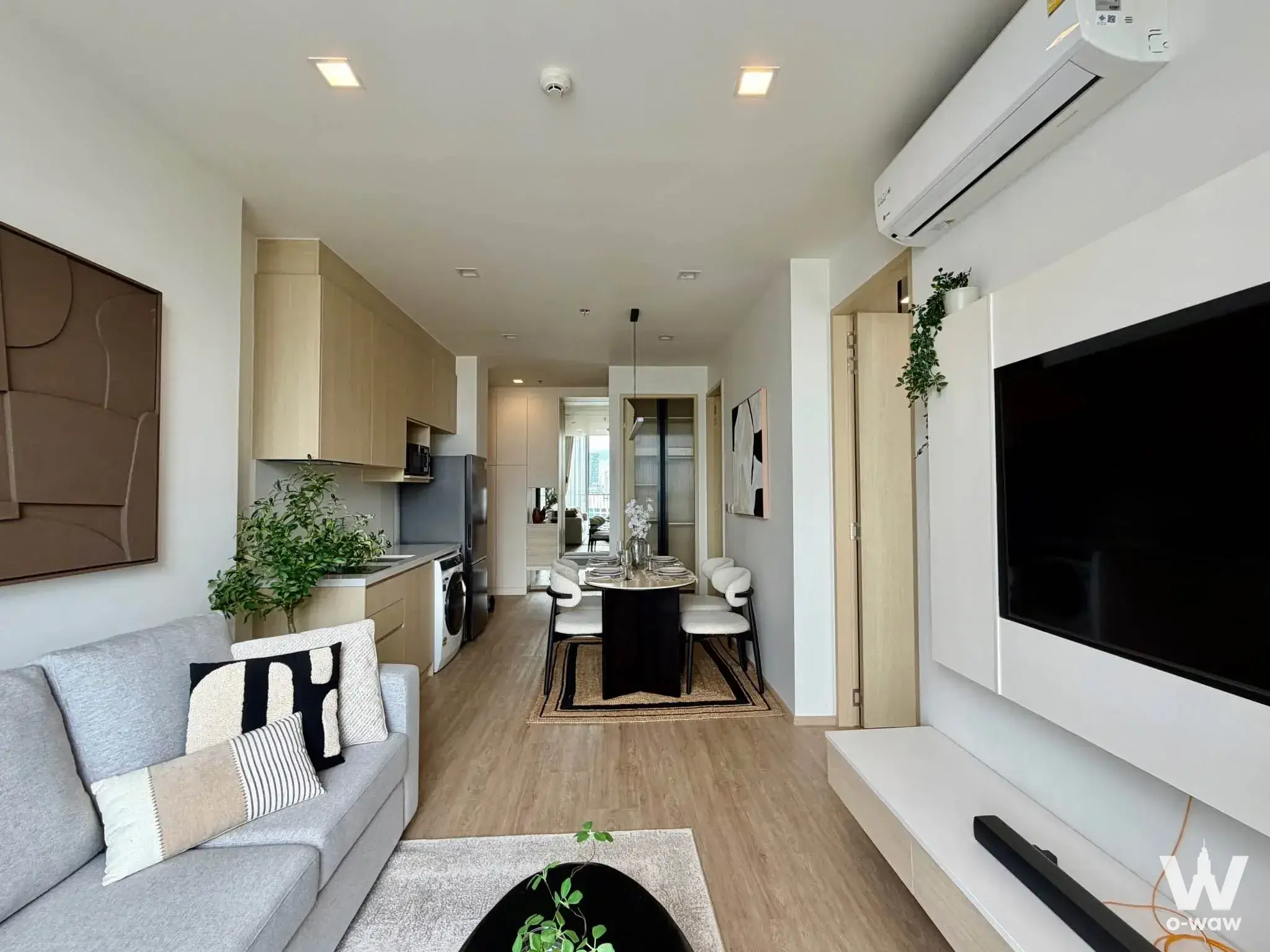 Open-plan space in Noble State 39 combining grey sofa, marble dining table, and kitchen