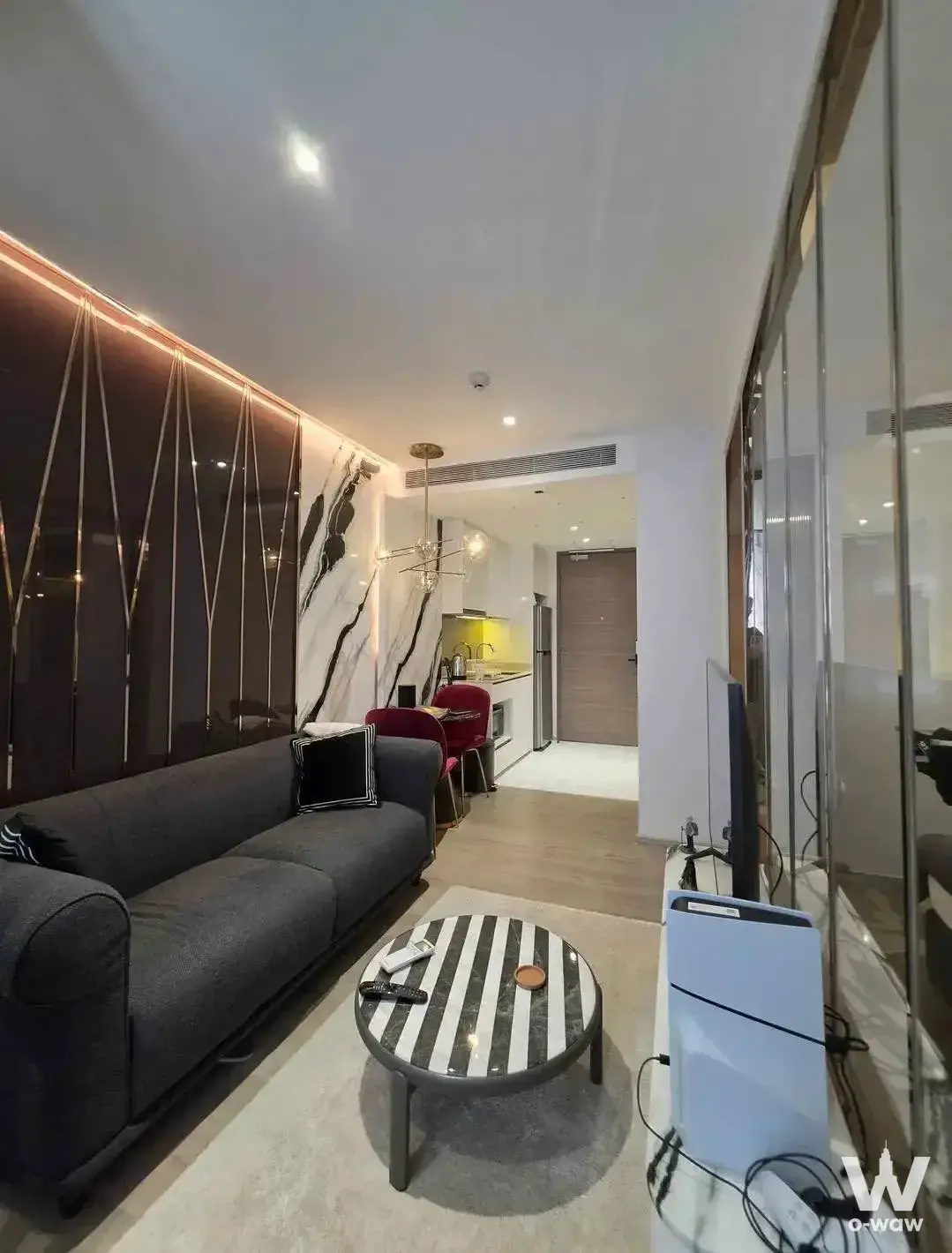 Dark glossy feature wall with gold inlay and marble accents in a Fynn Asoke luxury condo living room