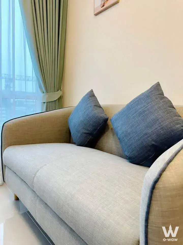 Beige sofa with blue pillows in a bright living room at The Sky Sukhumvit condo near BTS Udom Suk