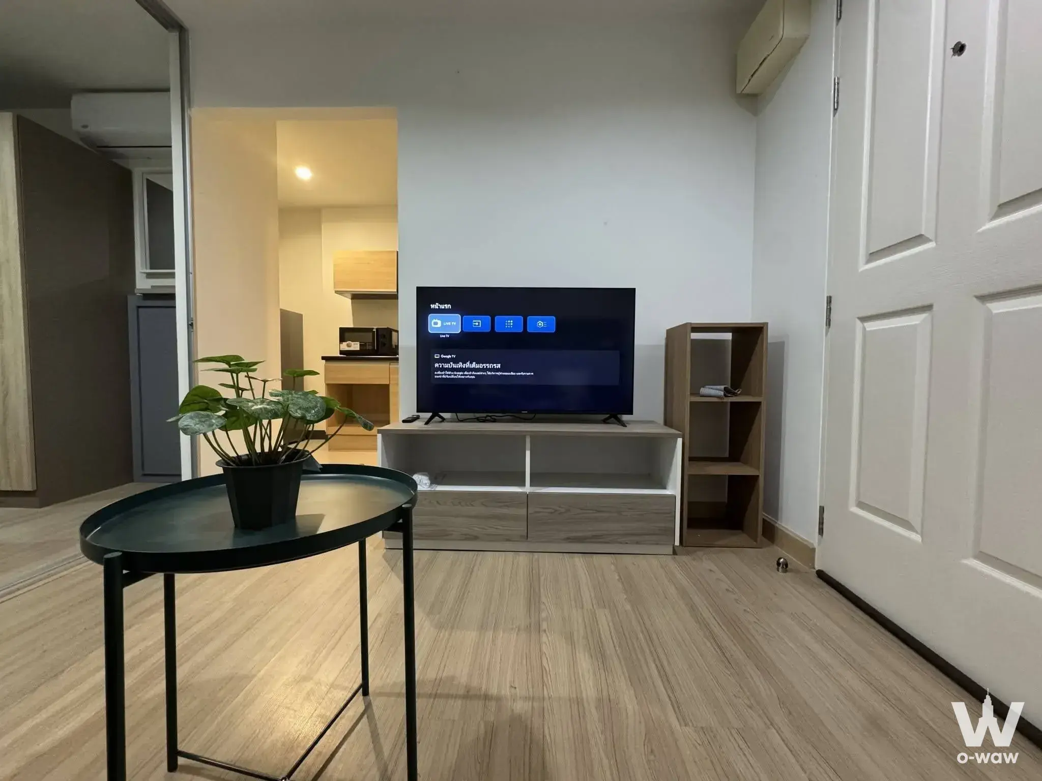 Minimalist living room with wood floors and TV in a Niche ID Seri Thai - Wongwaean condo
