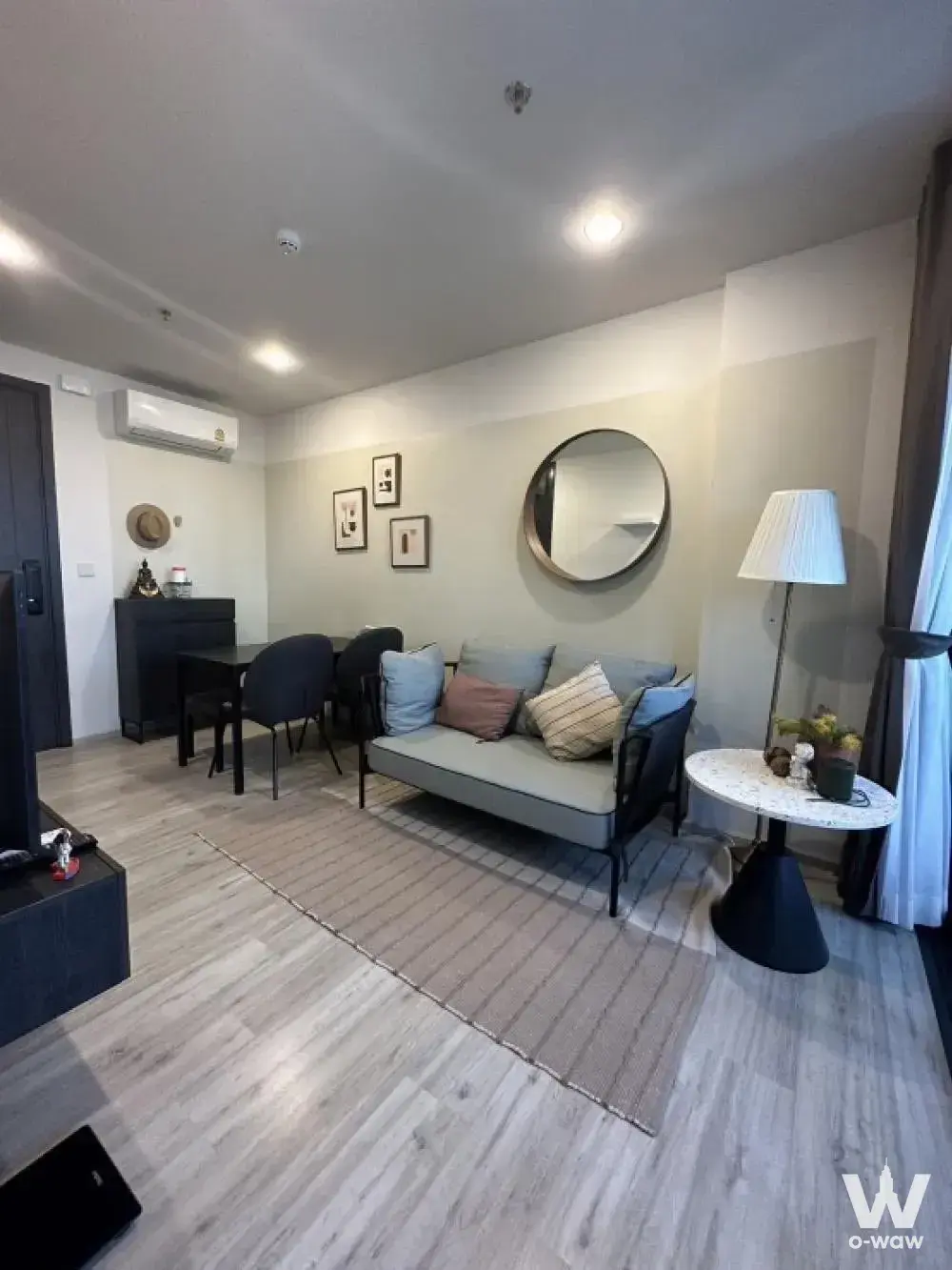 XT HUAIKHWANG 1-bed condo living space with grey sofa, gold mirror, and dining nook