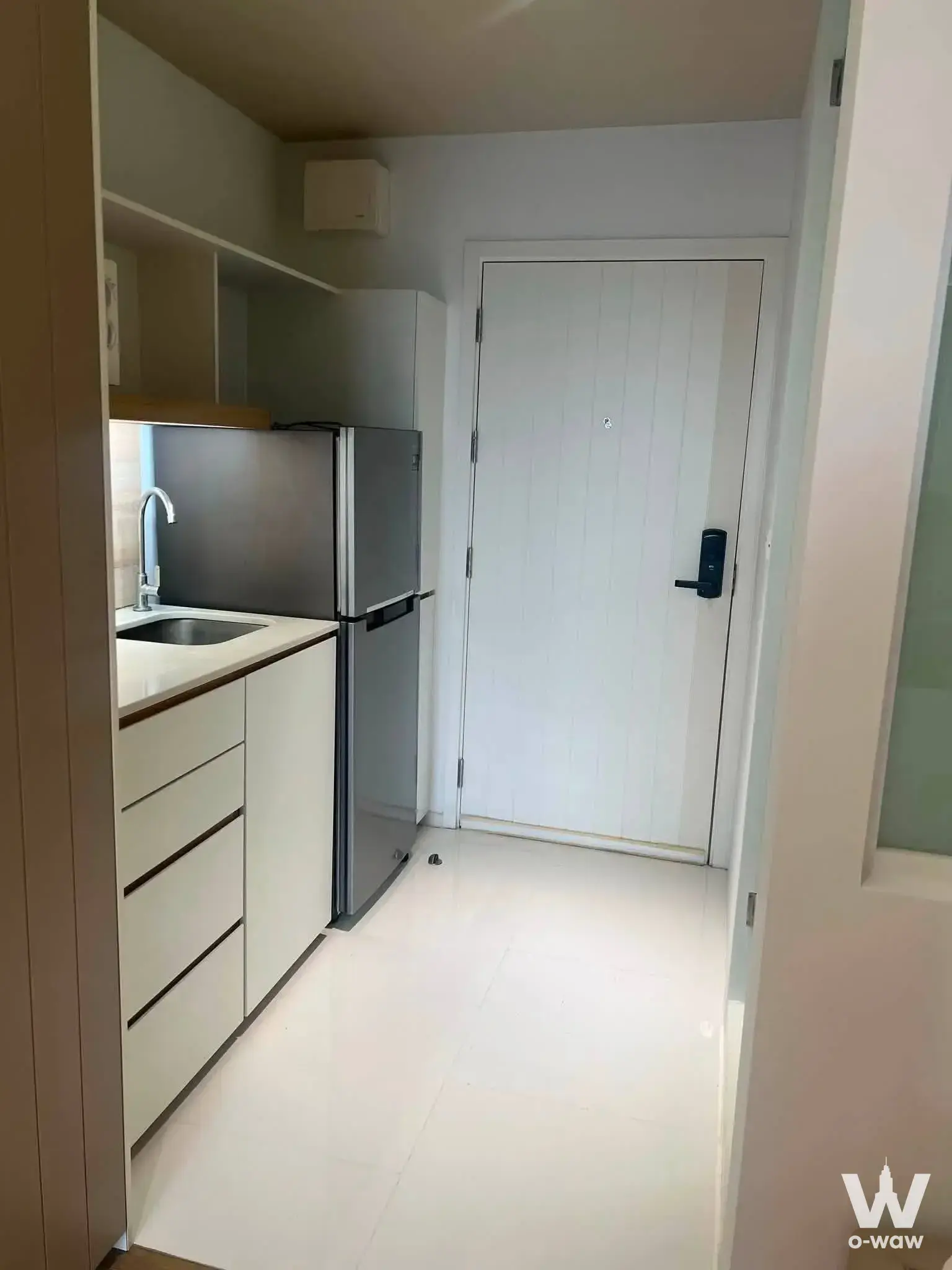 Bright entryway kitchenette in a Triple Y Residence condo for sale with white high-gloss cabinets and smart lock