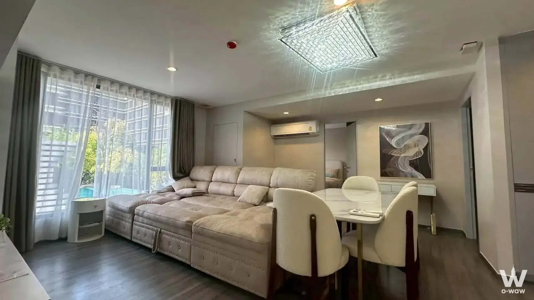 Luxury living room with crystal chandelier, beige sectional sofa, and marble dining table in an Ideo Mobi Sukhumvit 40 condo