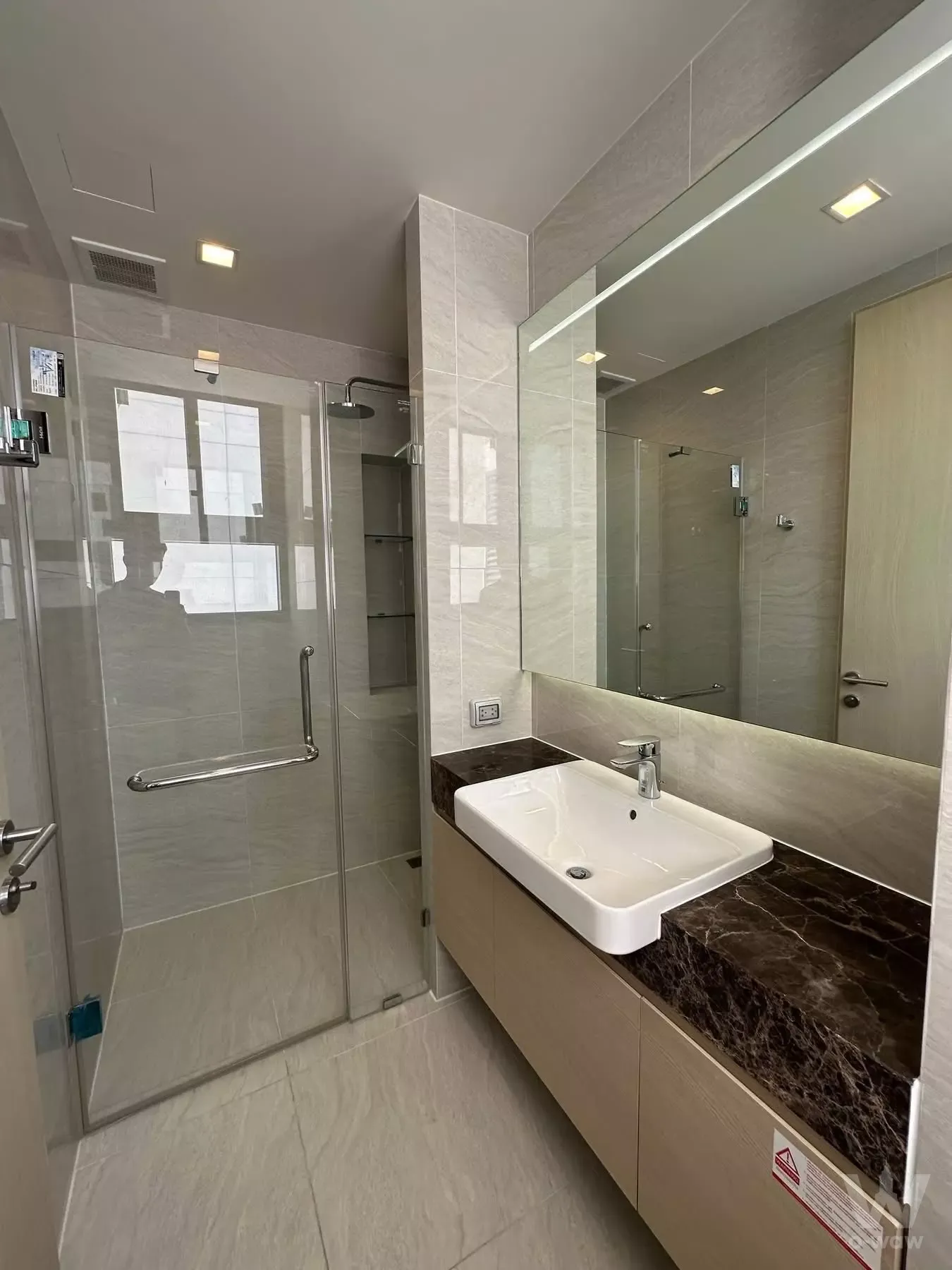 Modern bathroom in Noble State 39 featuring a glass walk-in shower and floating vanity with dark granite countertop