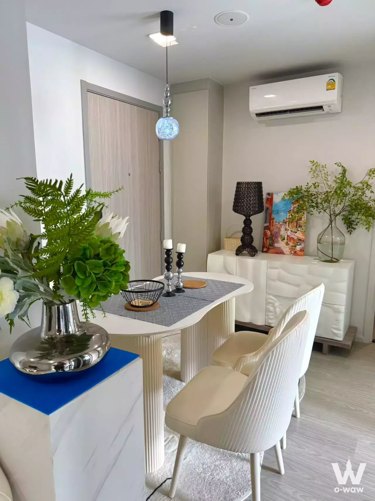 Modern dining area with white oval table and cream chairs in a 2-bed condo for rent at Atmoz Oasis Onnut