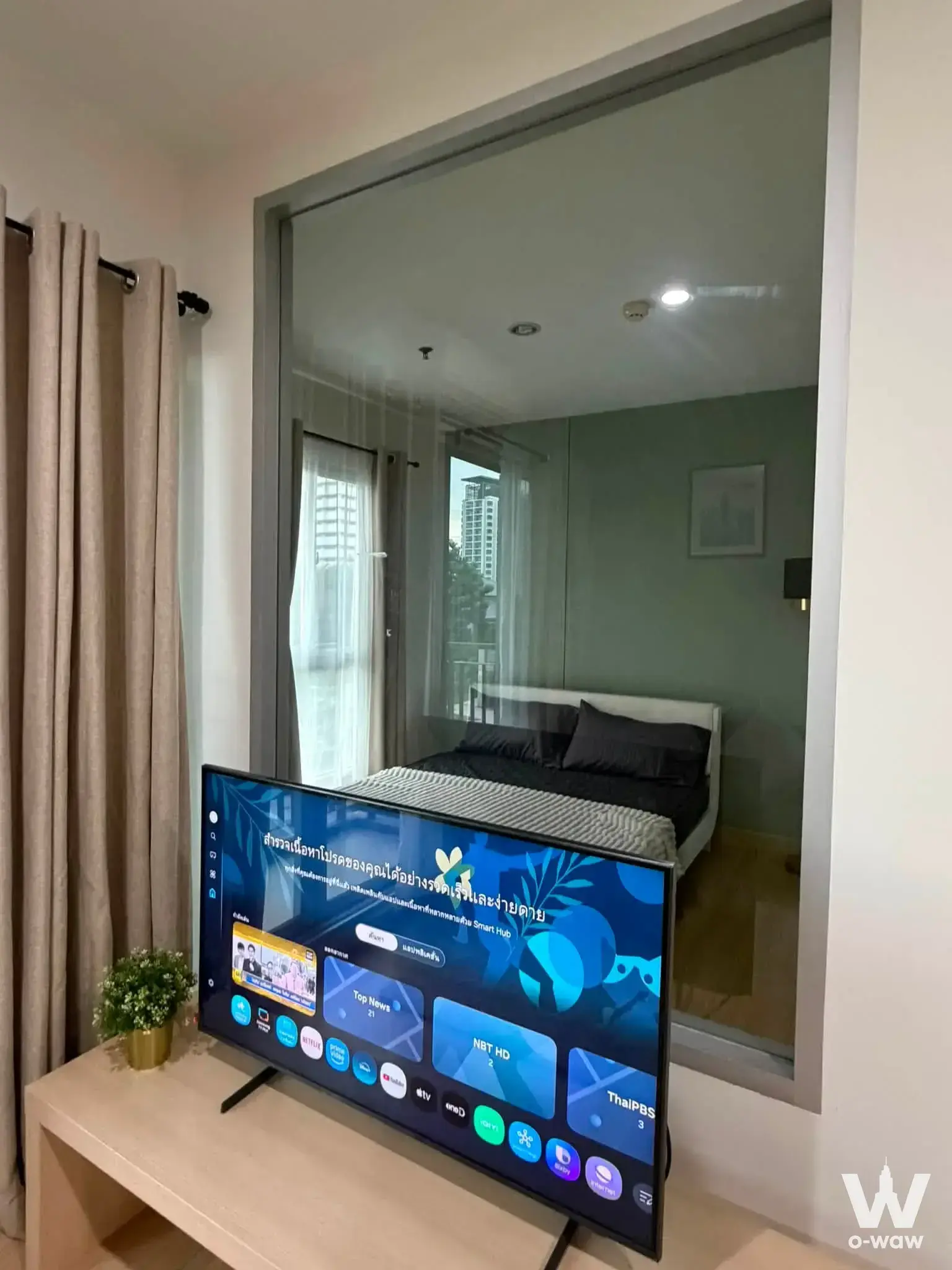 Open-plan living area in 1-bed condo at The Parkland Srinakarin Lakeside featuring glass partition to bedroom