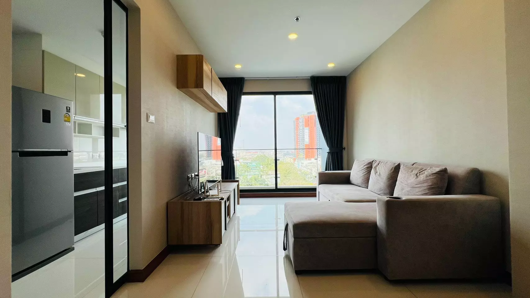 Beige sectional sofa facing city view through sliding doors in Supalai Premier Charoen Nakhon