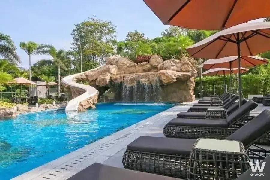 Luxury resort swimming pool with water slide, lounge chairs, and tropical landscaping
