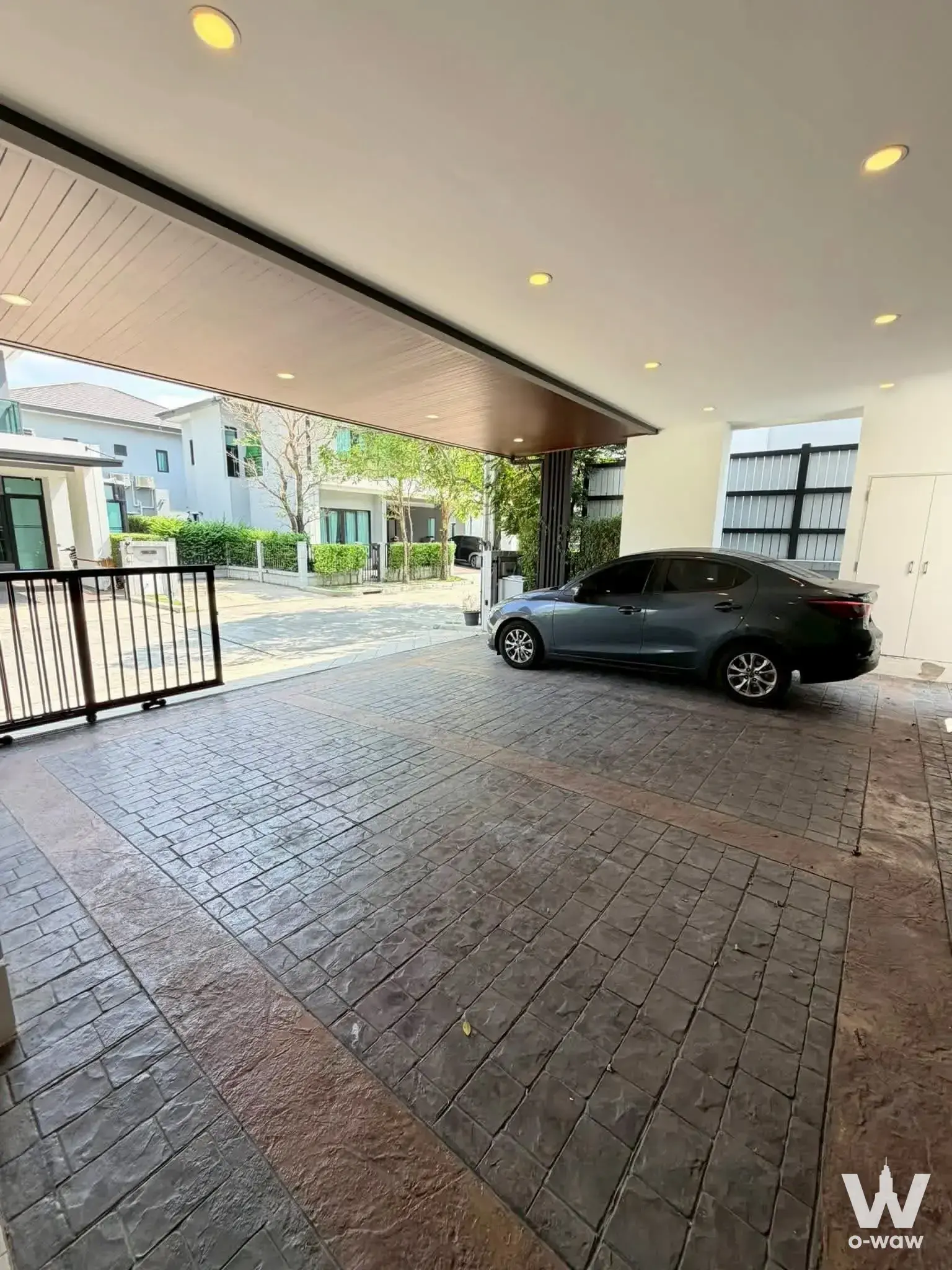 Modern detached house exterior with dark grey pavers and white stucco walls for sale in The City Watcharapol