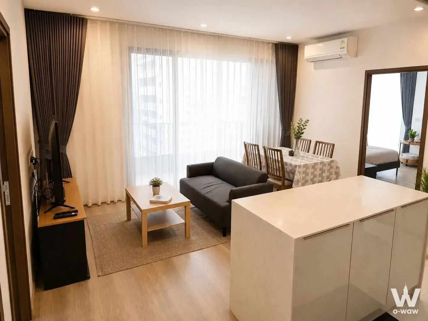 Modern furnished living room with sofa, TV console, and dining area in Ideo Mobi Sukhumvit 66 condo for rent