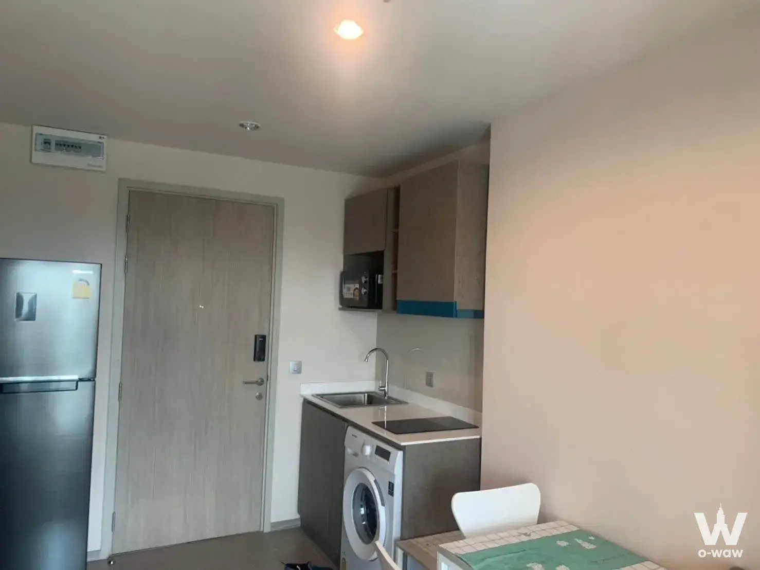 Compact kitchenette in this Aspire Erawan Prime condo features grey cabinets, a black induction cooktop, and integrated