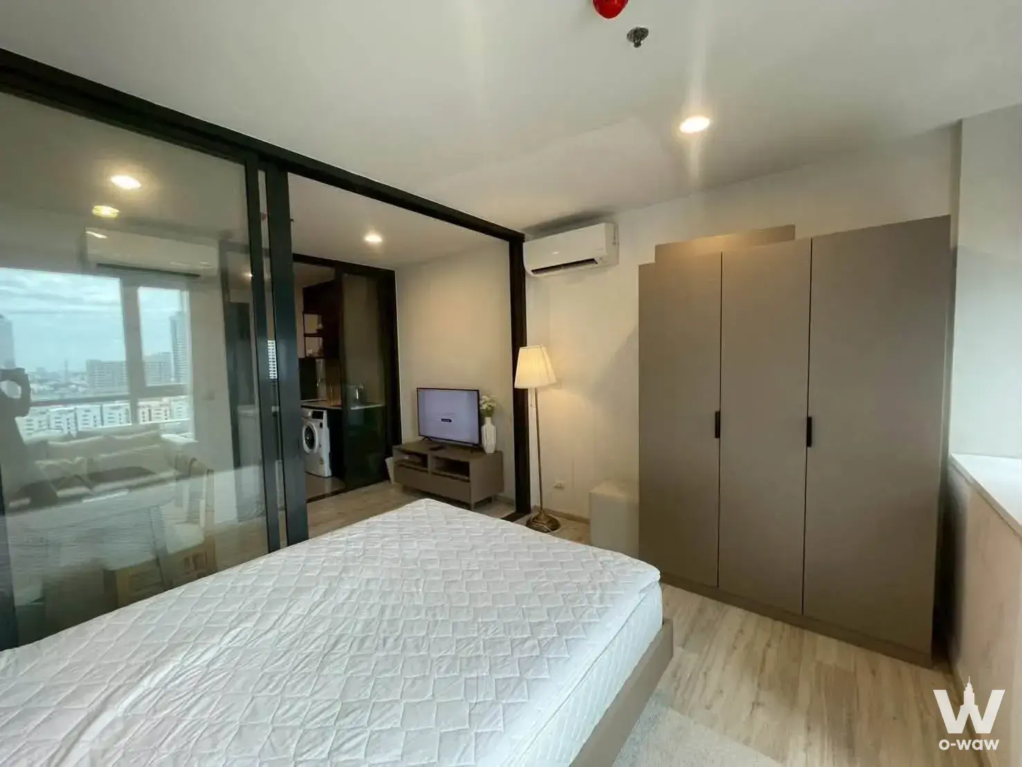 1-bed condo for rent in XT HUAIKHWANG featuring a queen bed, floor-to-ceiling wardrobe, and city view through glass partition