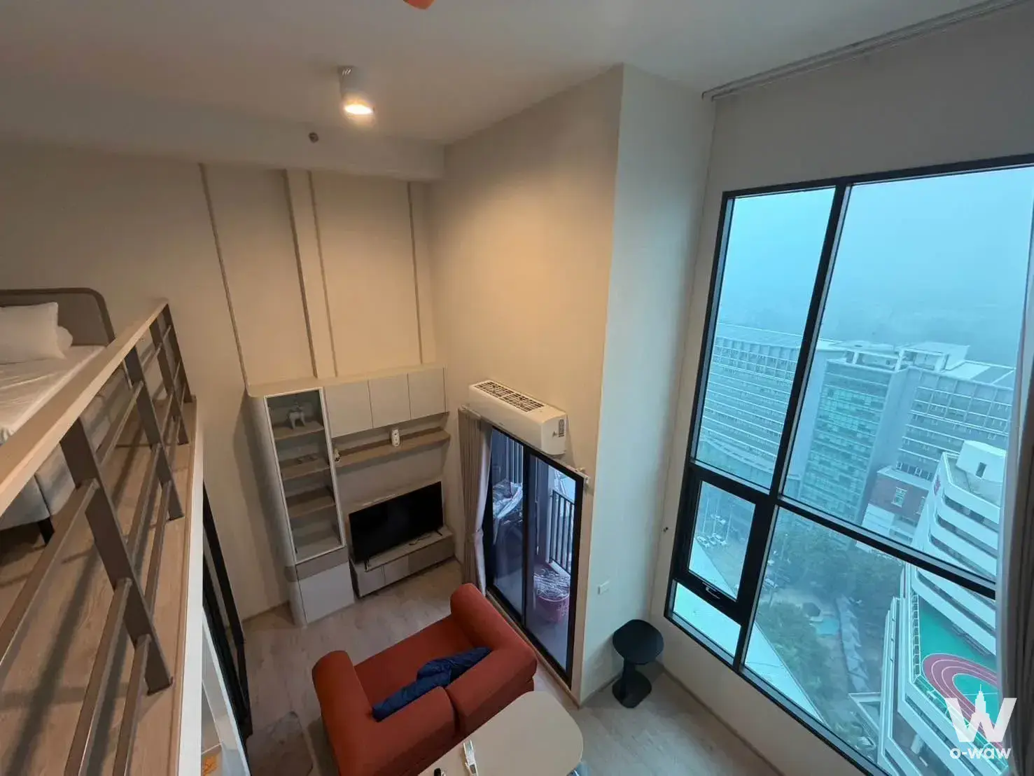 Loft bedroom in a COBE Kaset-Sripatum condo featuring a bunk bed and large windows overlooking the city skyline