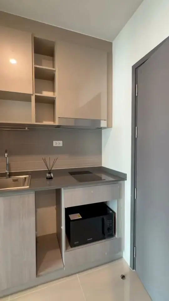 Ideo Ramkhamhaeng kitchenette with grey cabinetry, stone countertop, and induction cooktop