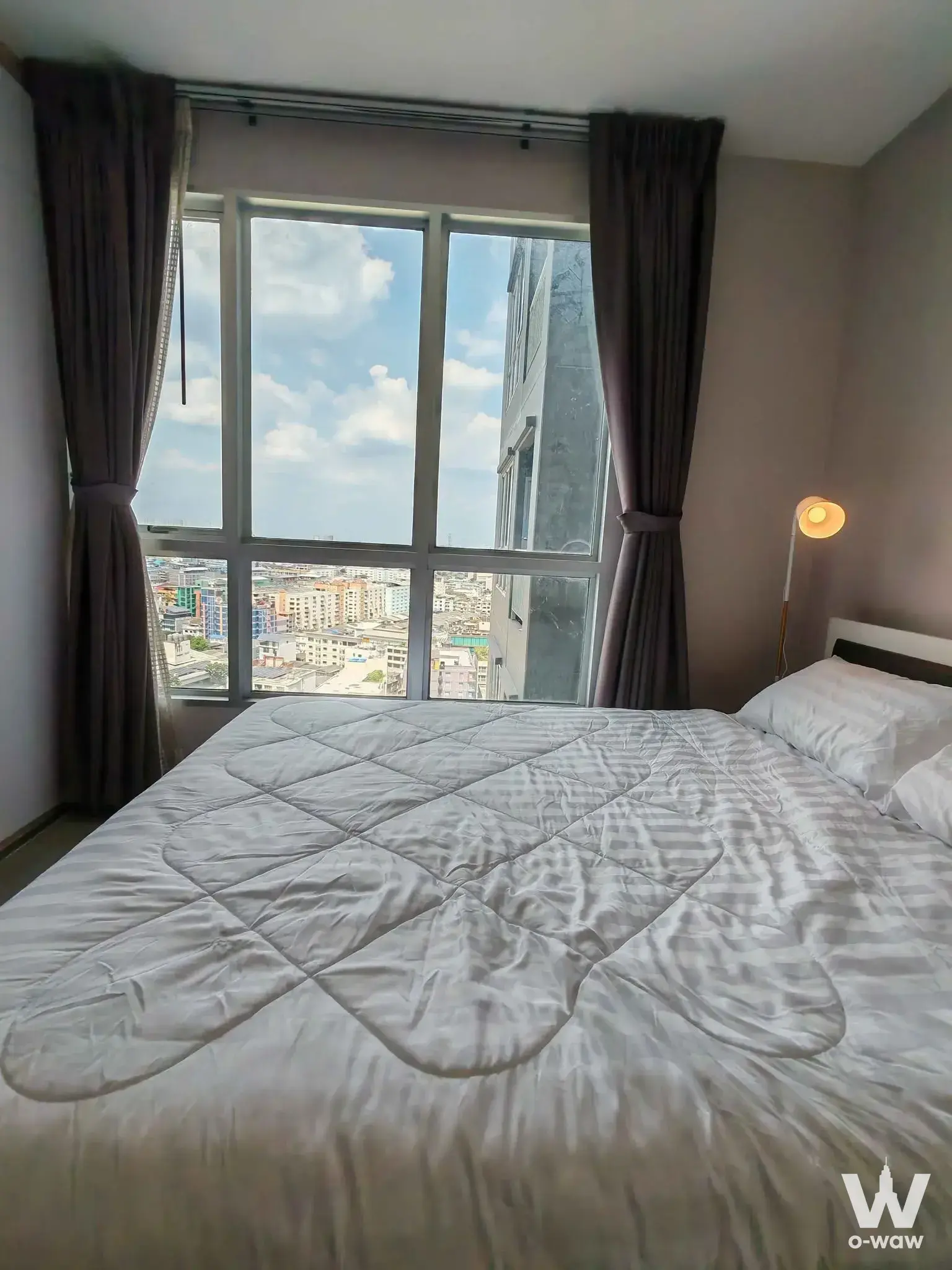 Life@Ratchada-Huai Khwang 1-bed condo bedroom with city skyline view and dark wood headboard