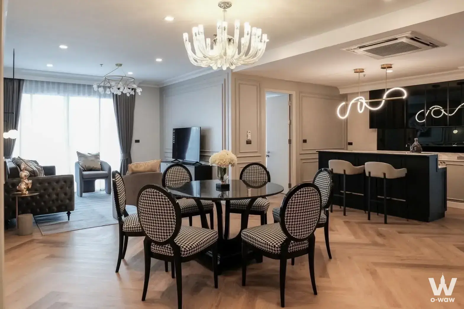 Open-plan living and dining area in a 3-bed Nusasiri Grand Condo with herringbone floors and crystal chandelier