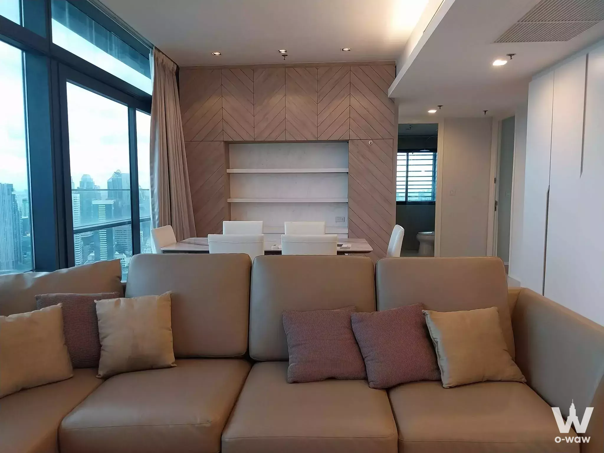 Living room with tan leather sectional and city views in a 3-bed condo for rent at Circle Living Prototype