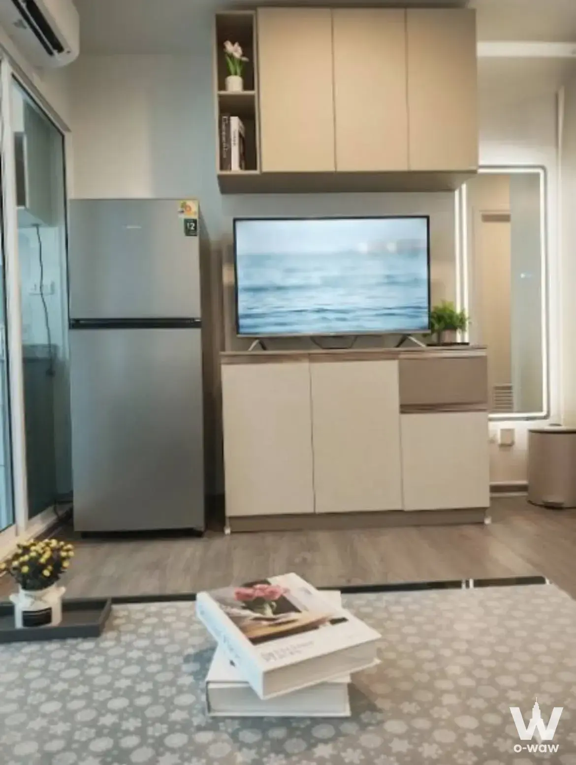 Compact living area in a Regent Home Bangna studio with built-in cabinets and flat-screen TV