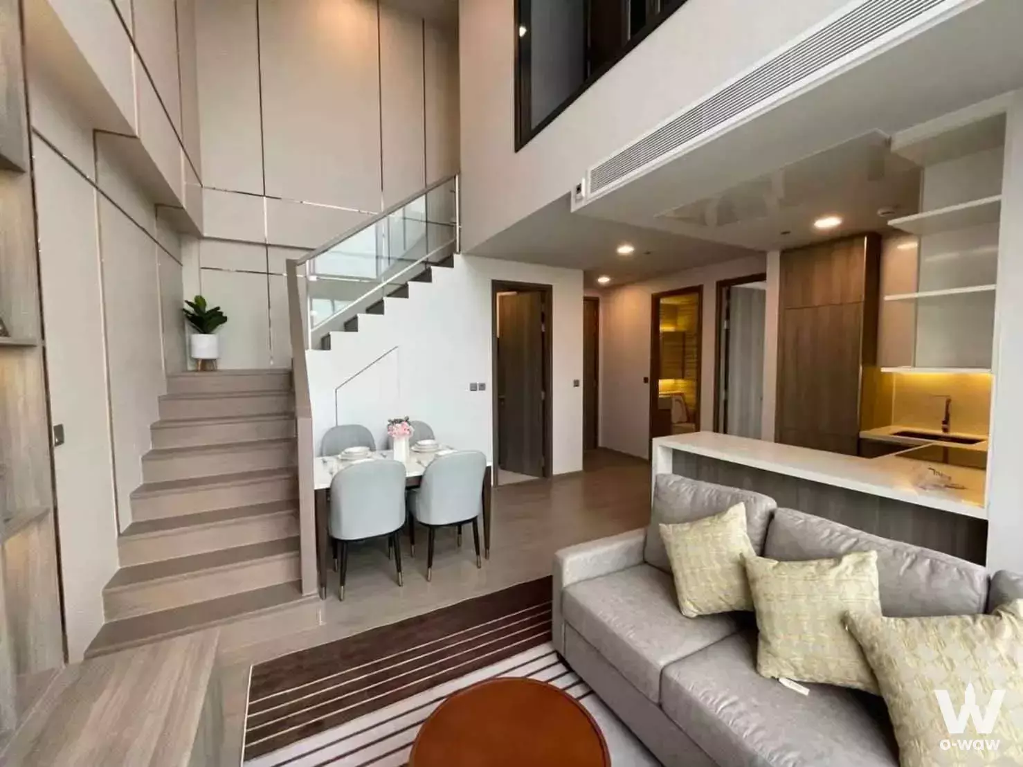 Open-plan duplex living room with floating staircase and dining nook in a 2-bed condo for rent at Celes Asoke