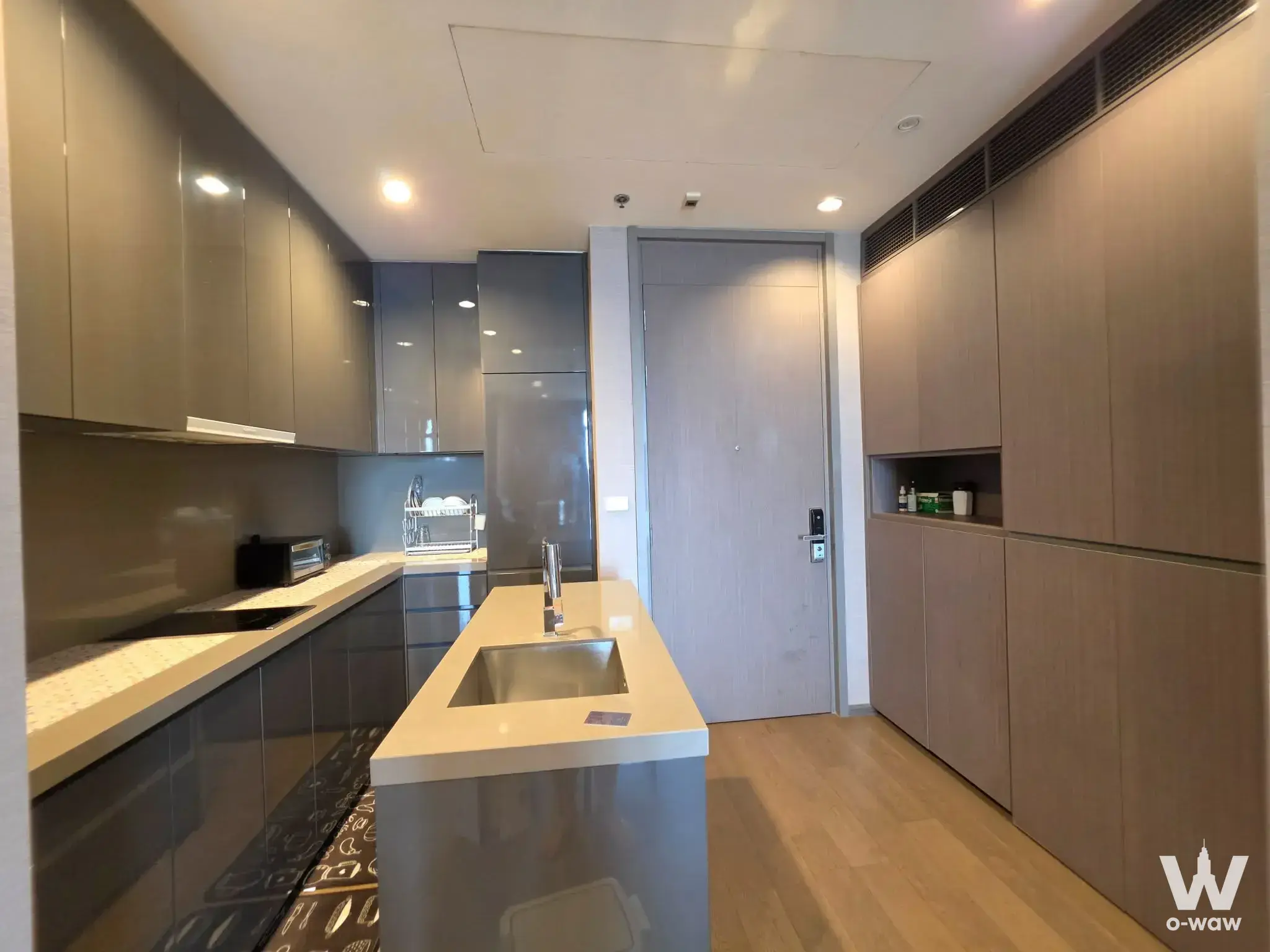 Modern kitchen in The Diplomat Sathorn with central island, induction cooktop, and glossy grey cabinetry