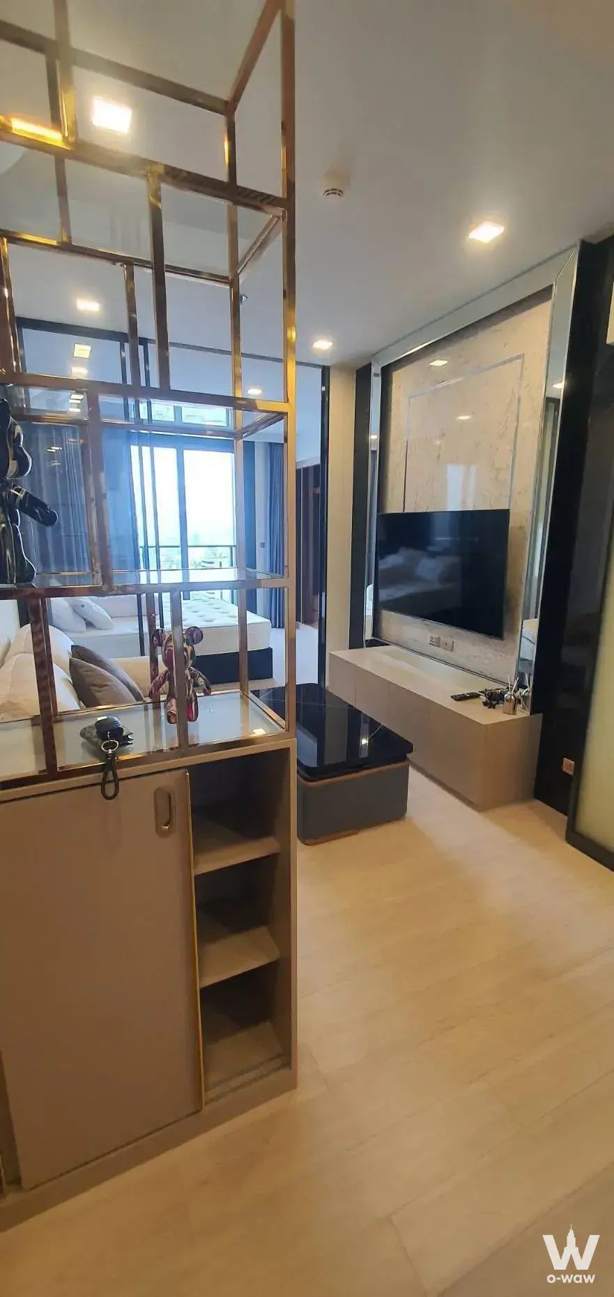 Studio living area with gold room divider, marble TV wall, and grey sofa at Chapter One Eco Ratchada-HuaiKhwang