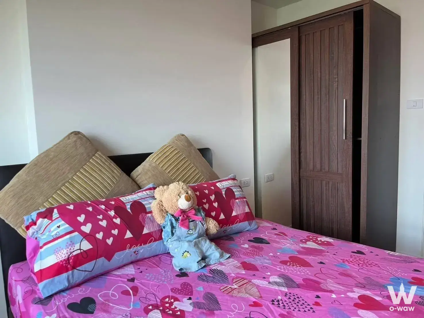 Compact bedroom in Lumpini Ville Pattanakarn 1-bed condo with queen bed, pink duvet, and dark wardrobe